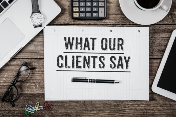 What Our Clients Say statement on notepad on office desk from above
